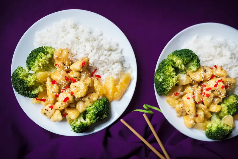 Top view of Asian chicken stir fry with rice and broccoli on a white plate