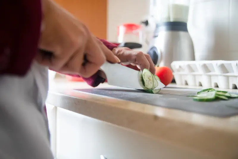 Close-up of a person slicing cucumbers on a kitchen counter for a healthy meal prep