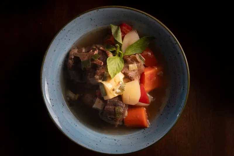 A delicious beef stew with colorful vegetables served in a blue bowl, perfect for a cozy meal