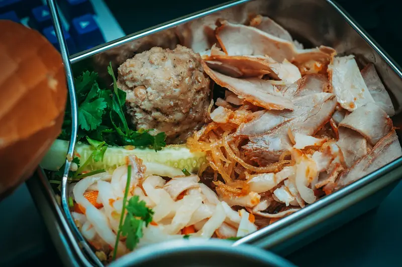 Delicious sliced meat and vegetables packed in a metal lunch box for a flavorful meal