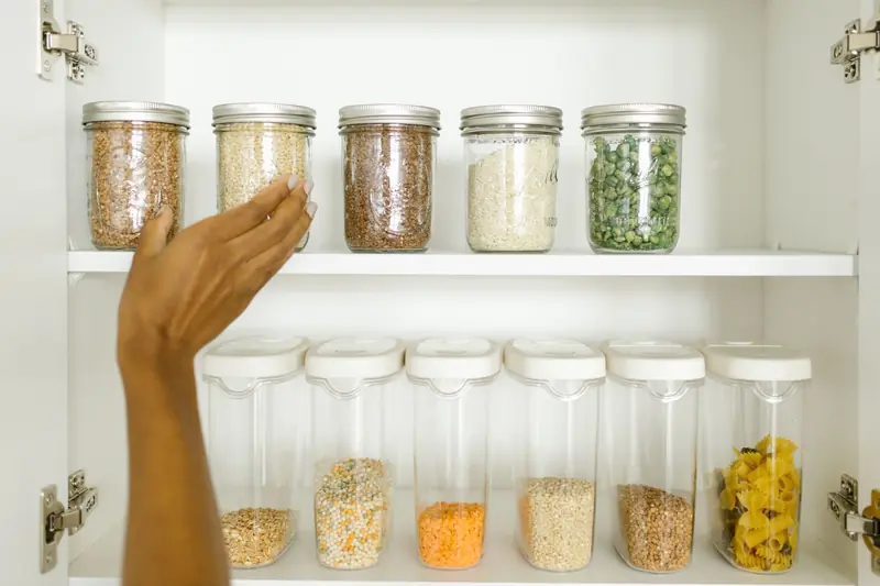 A neat pantry shelf showing various grains stored in labeled glass and plastic containers, promoting kitchen organization